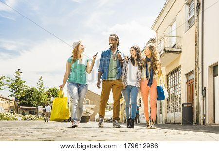 Multiracial friends group having fun together walking on town street - Everyday lifestyle and friendship concept on springtime - Young people hanging out together after shopping - Bright vivid filter