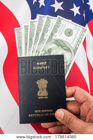 concept showing Indian passport with US currency notes or Dollars with american flag in the background, applying for US / american tourist or H-1B visa