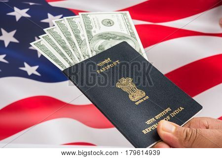 concept showing Indian passport with US currency notes or Dollars with american flag in the background, applying for US / american tourist or H-1B visa