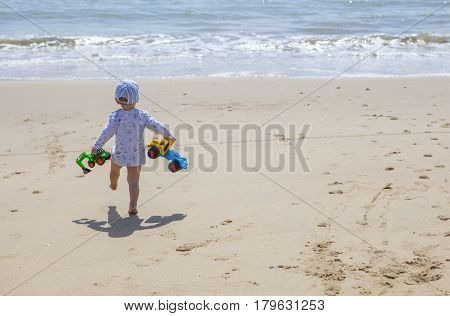 Baby boy walking with toys at the beach. El Rompido Cartaya Huelva Spain