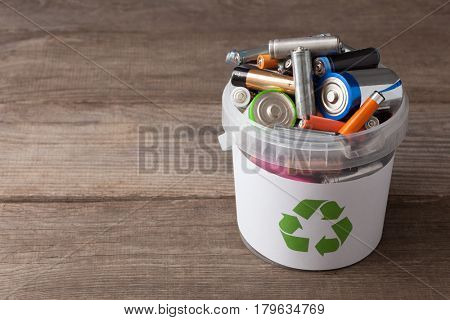 battery recycle bin with old element on wood table