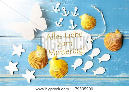 Flat Lay View Of Label With German Text Alles Liebe Zum Muttertag Means Happy Mothers Day. Sunny Summer Greeting Card. Butterfly, Shells And Fishes On Blue Wooden Background