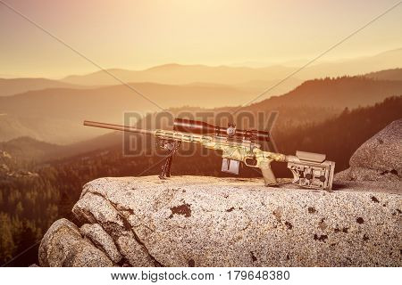 The Rifle Lies On A Rock Mountains In The Background