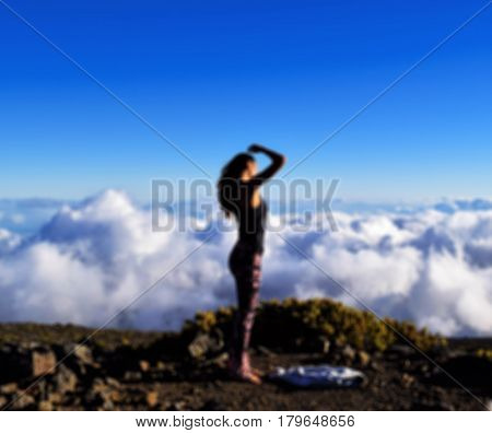 The girl on the mountain above the clouds in blurred for background
