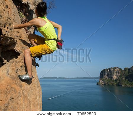 free solo woman rock climber climbing at seaside cliff