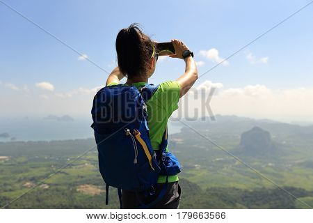 successful woman hiker taking photo with cellphone hiking on mountain peak