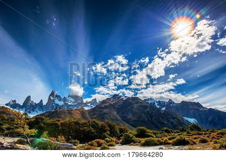 Mount Fitz Roy in Patagonia in Argentina and its neighboring granite towers with lens flare from the sun as seen from hike towards Laguna de los Tres