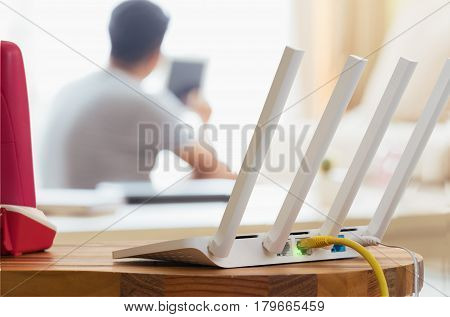 closeup of a wireless router and a man using smartphone on living room at home ofiice