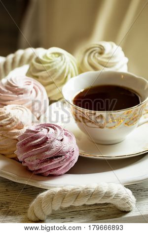 Sweet homemade dessert - marshmallow (zephyr) with cup of tea.Homemade marshmallows on a light background. Russian currant and mango zephyr.
