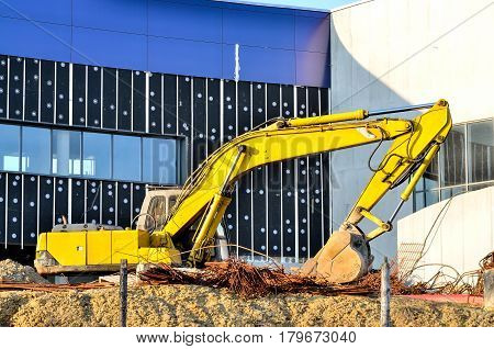 Excavator on a construction site. Yellow excavator at the construction of a new swimming pool in the city.