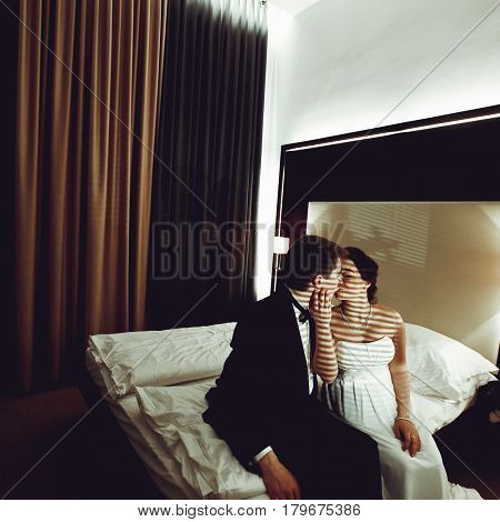 Bride Kises A Groom Sitting With Him On A Bed