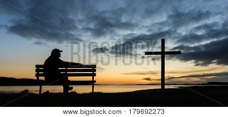 A man on a seat next to a cross at Foxton Beach river.