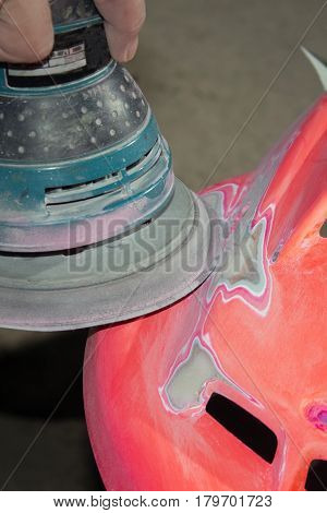 Work polishes the car body component preparation before painting.