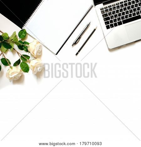 Modern minimalistic work place. White office desk table with laptop keyboard, pen, white roses. Top view with copy space, flat lay