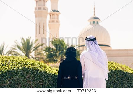 arabian couple standing in front of a mosque