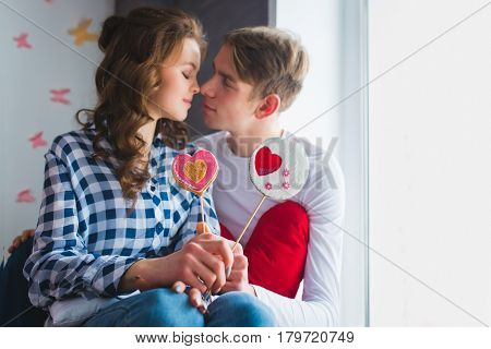 Beautiful couple having a fun together. Posing with lollipops on colorful background.