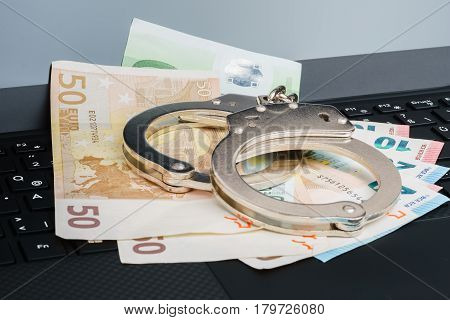 Money Under Handcuffs On The Laptop Keyboard. Hacker Crime Concept.