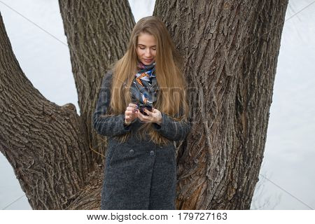 Portrait Of A Beautiful Girl With A Phone In Early Spring Outdoors.