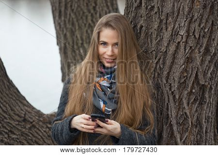 Portrait Of A Beautiful Girl With A Phone In Early Spring Outdoors.
