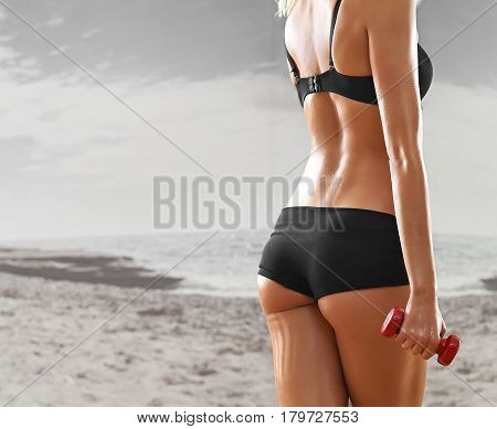 Sexy, athletic, blonde woman in the gym, against the background of the mirror, with dumbbells in hands. Sports, sportswear, health, a beautiful body, full-length portrait, body Parts