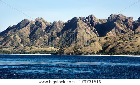 Green vegetation mountain landscape with white beach and blue coastline sea at its foot at Labuan Bajo Bajawa Indonesia.