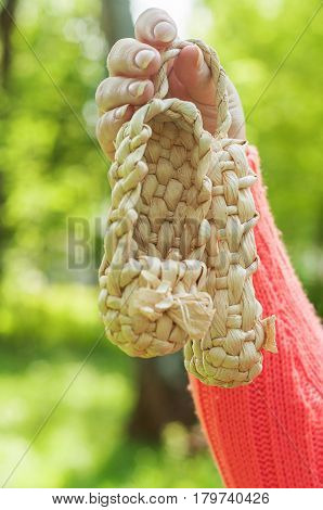 Pair of brown color straw shoes hand.
