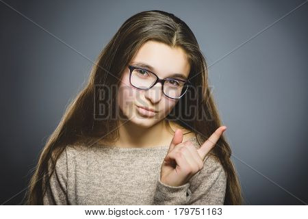 displeased and contemptuous girl with threatens finger isolated on gray background