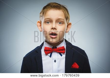 Closeup Portrait of handsome boy with astonished expression while standing against grey background.