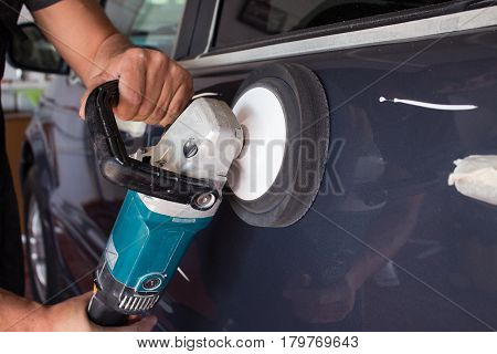 A man's hand holds a car polishing tool