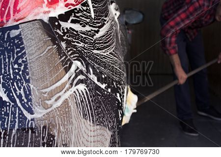 black car with white foam in the carwash