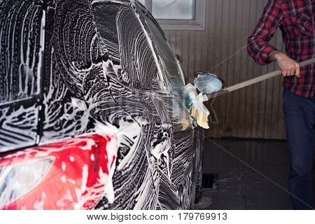 black car with white foam in the carwash