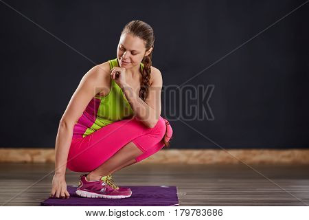 Young slim woman in yoga class making beautiful asana exercises. Healthy lifestyle in fitness club. Woman in the sportwear, pink legginga and green t-shirt. In the yogastudio on the violet yoga mat.