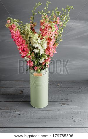 Delphinium of pink color and lemon in vintage vase on gray background.