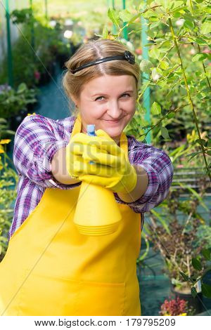 Woman gardener sprays water on you, and smiling