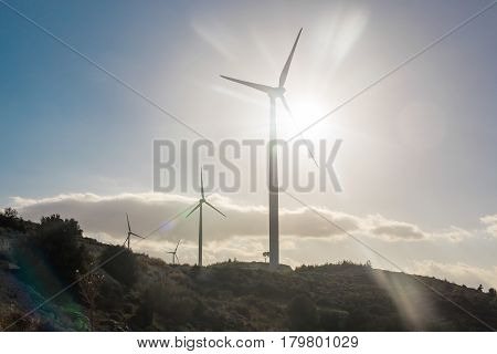 Green renewable energy concept - wind generator turbines in sky.