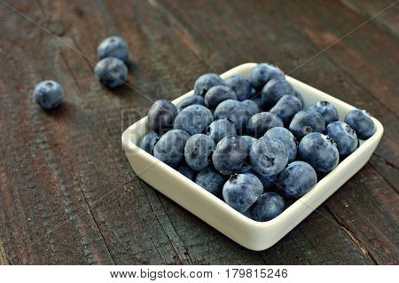 Blueberry fruit on wood background. Forest fruit in white idaeus. Delicious fresh berries.