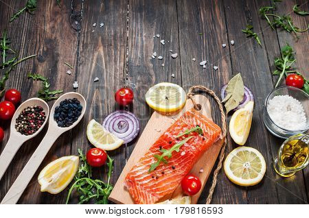 Delicious portion of fresh salmon fillet with aromatic herbs spices and vegetables - healthy food diet or cooking concept. Top view and copyspace.