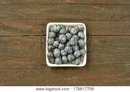 Blueberry fruit on wood background. Forest fruit in white idaeus. Delicious fresh berries.
