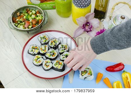 Hand taking home made sushi from a plate