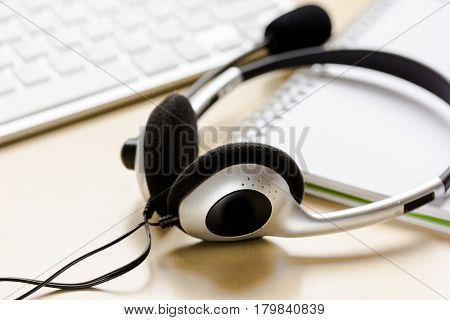 operator headset and computer keyboard on workdesk for call center concept on beige background