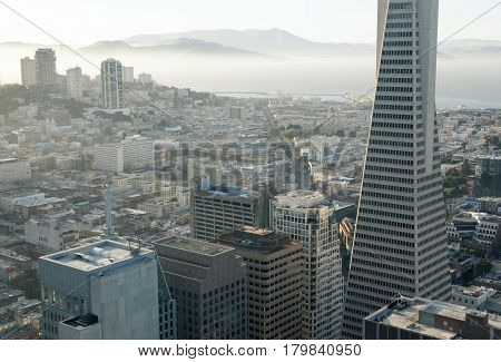 Aerial view of San Francisco Downtown and San Francisco Bay. Financial District neighborhood and hazy San Francisco bay in the background. High angle shot late afternoon.