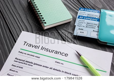 Travel insurance application form with flight tickets and passport on gray wooden desk background