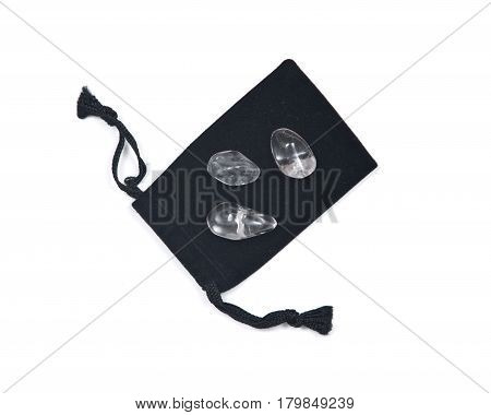 Tumbled clear quartz on black velveteen crystal pouch isolated on white background