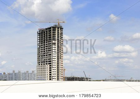 Under construction building with the crane and the sky.