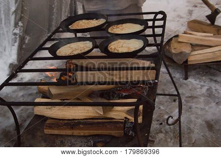 The pancakes are fried in a pan outdors - maslenitsa carnival, close up