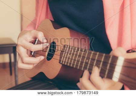 A woman playing ukulele in close up view.