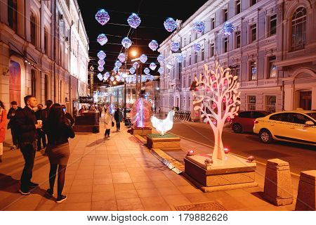 MOSCOW RUSSIA - May 02 2016. Street festival Moscow Spring. Flower illuminated decoration of colorful fair. People walking in the evening.