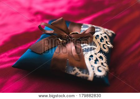 Weddings ring on the blue pillow on red background