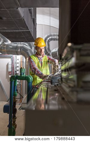 Worker making final touches to HVAC system. HVAC system stands for heating ventilation and air conditioning technology. Team work HVAC indoor environmental comfort concept photo.