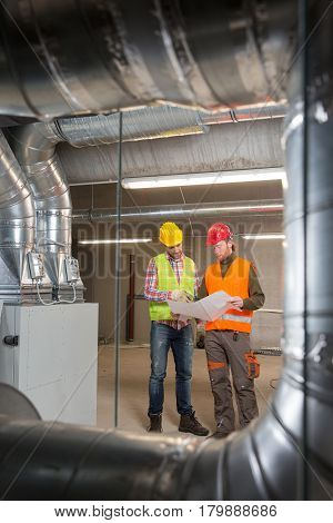 Workers making final touches to HVAC system. HVAC system stands for heating, ventilation and air conditioning technology. Team work, HVAC, indoor environmental comfort concept photo.